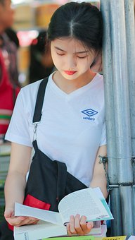 młoda dziewczyna opierając się o ścianę czyta książkę