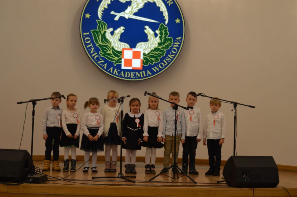 Przegląd Piosenki Patriotycznej i Harcersskij Powiatowej Biblioteki Publicznej w Rykach, scena, grupa małych dzieci śpiewa