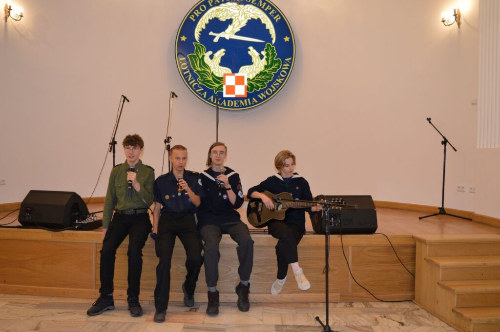 Przegląd Piosenki Patriotycznej i Harcersskij Powiatowej Biblioteki Publicznej w Rykach, scena, 4 osoby - młodzież śpiewa
