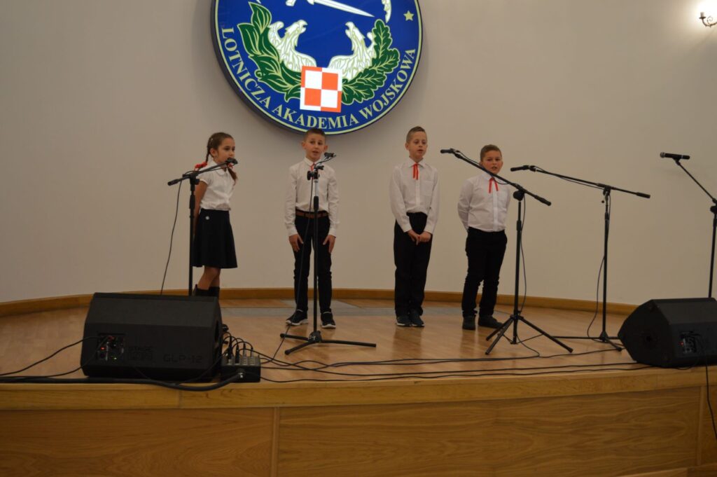 Przegląd Piosenki Patriotycznej i Harcersskij Powiatowej Biblioteki Publicznej w Rykach, scena, czworo dzieci śpiewa