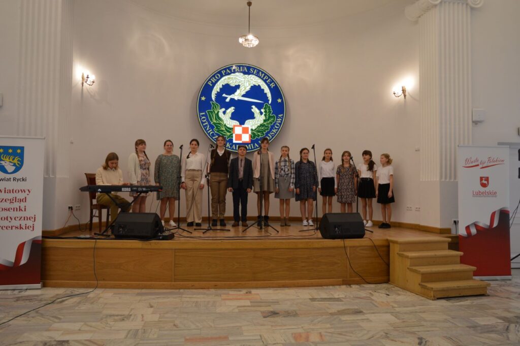 Przegląd Piosenki Patriotycznej i Harcersskij Powiatowej Biblioteki Publicznej w Rykach, scena, grupa ludzi śpiewa