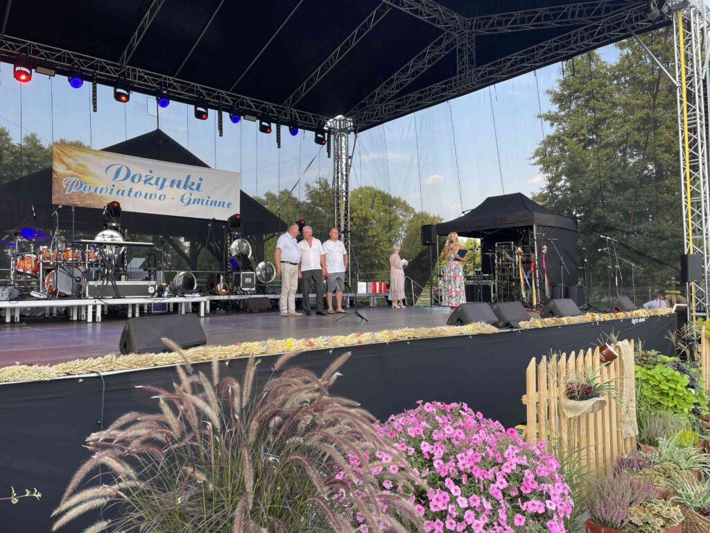 dożynki powiatowo- gminne, trzy osoby na scenie
