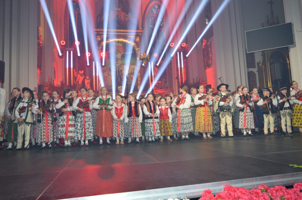 skrzypek w świetle reflektorów dyryguje zespołowi Mała Armia Janosika