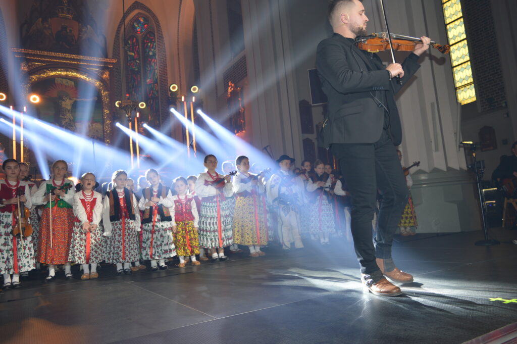 skrzypek w świetle reflektorów dyryguje zespołowi Mała Armia Janosika