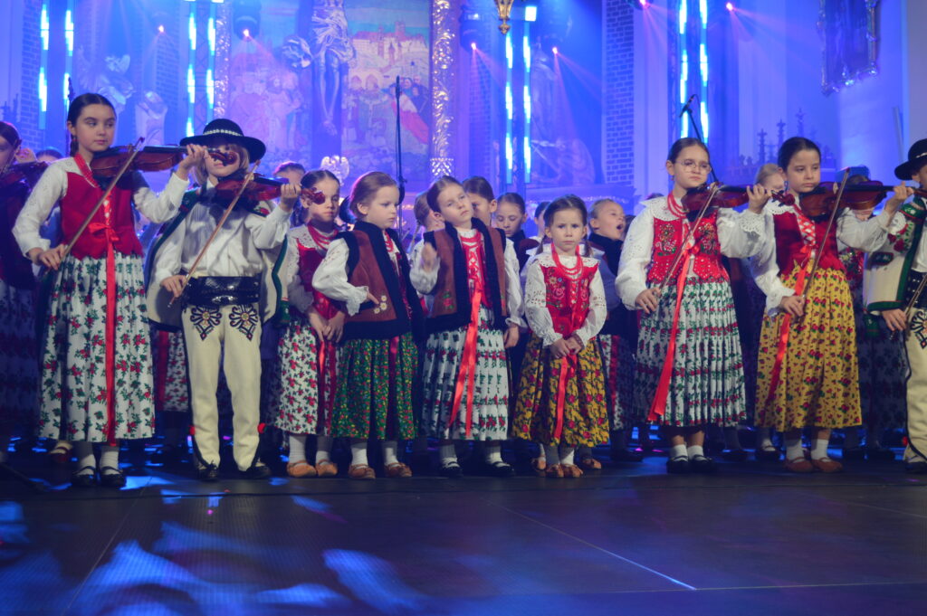 skrzypek w świetle reflektorów dyryguje zespołowi Mała Armia Janosika