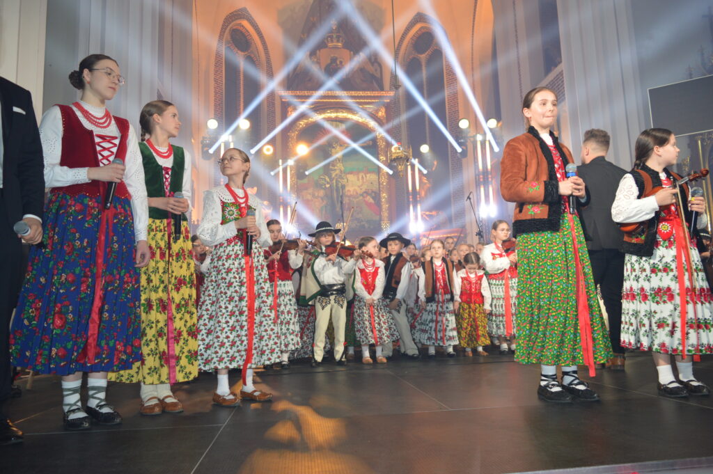 skrzypek w świetle reflektorów dyryguje zespołowi Mała Armia Janosika