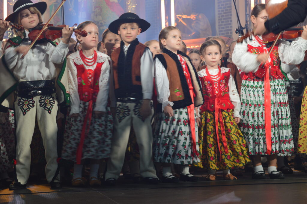 skrzypek w świetle reflektorów dyryguje zespołowi Mała Armia Janosika