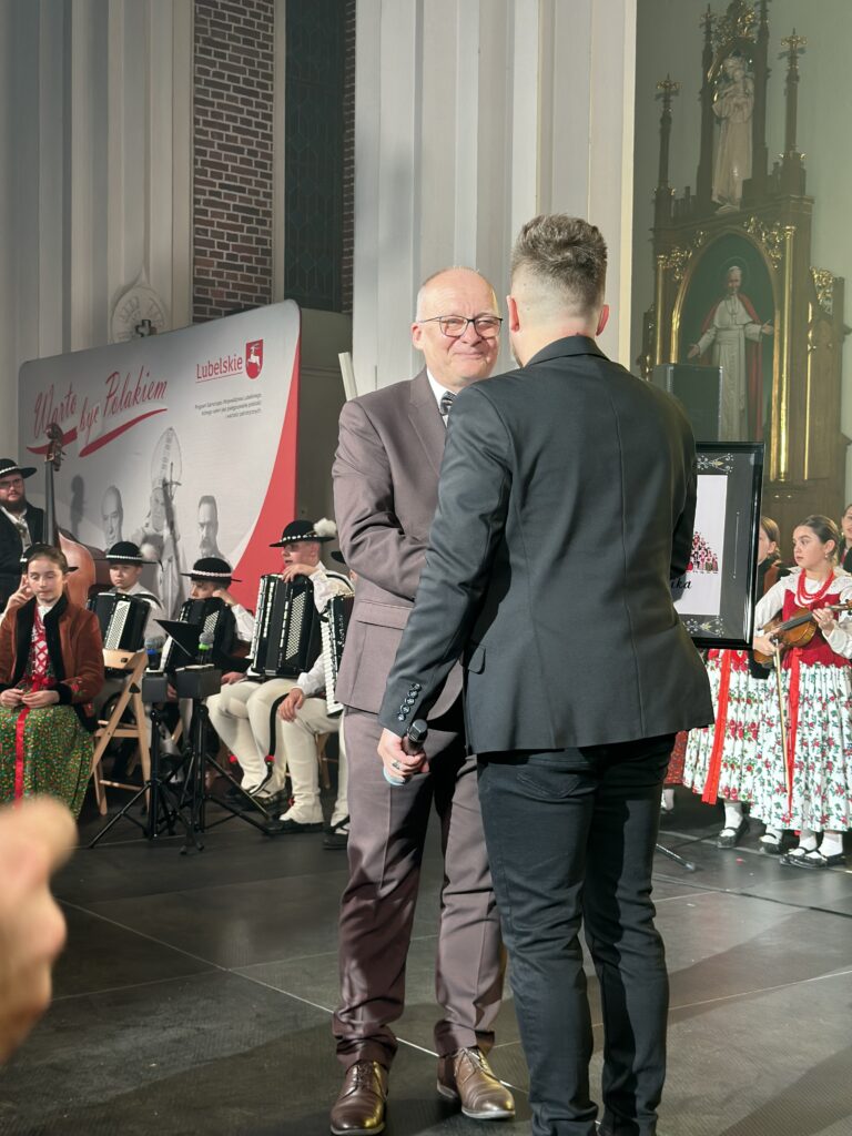 skrzypek z zespołu  Mała Armia Janosika wręcza pamiątkowe zdjęcie Staroście Ryckiemu