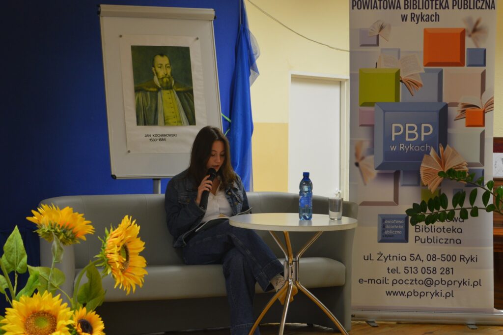 Czyta dziewczyna, siedzi, z boku żółte słoneczniki, tło narodowe czytanie, scena