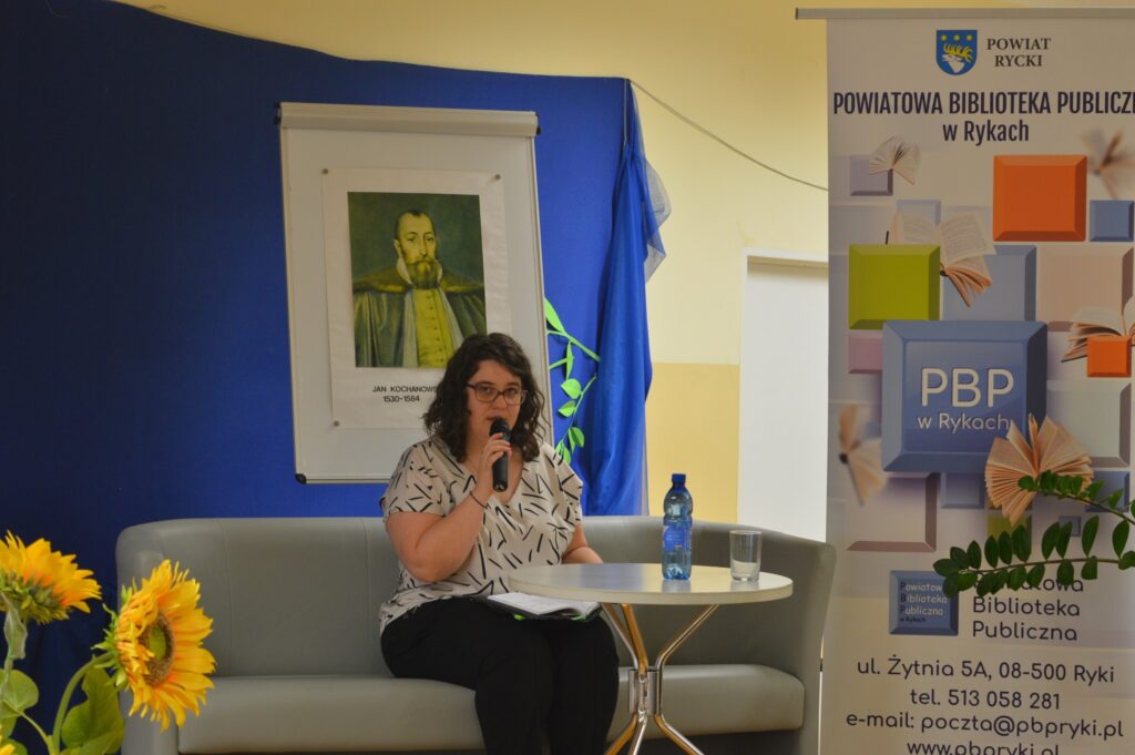 Czyta kobieta, siedzi, z boku żółte słoneczniki, tło narodowe czytanie, scena