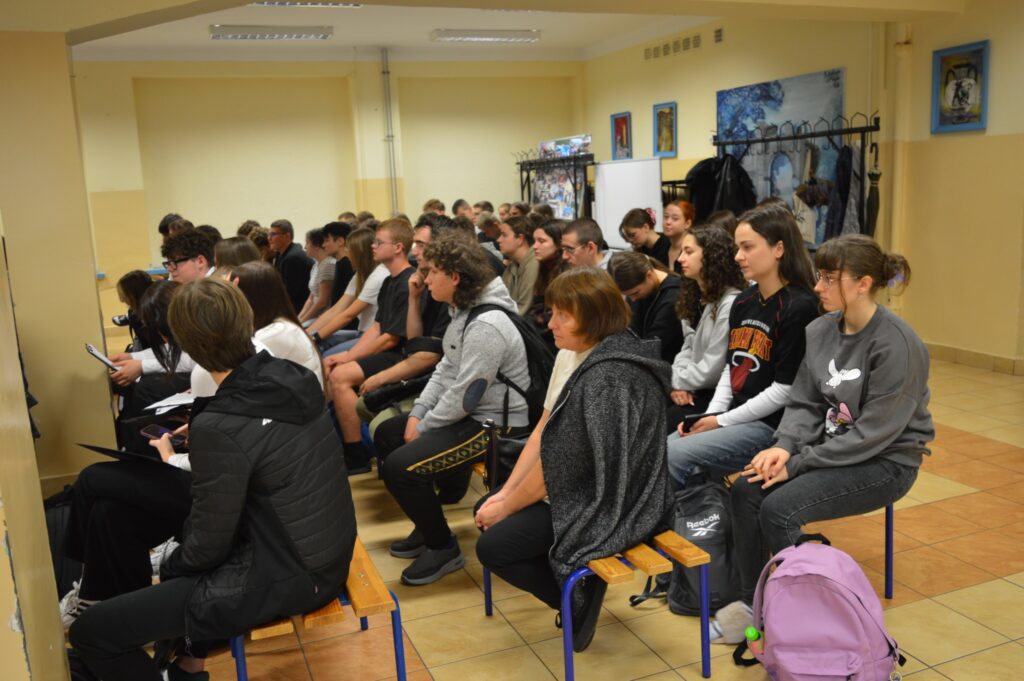 widownia siedzi, słucha, z boku żółte słoneczniki, tło narodowe czytanie, scena