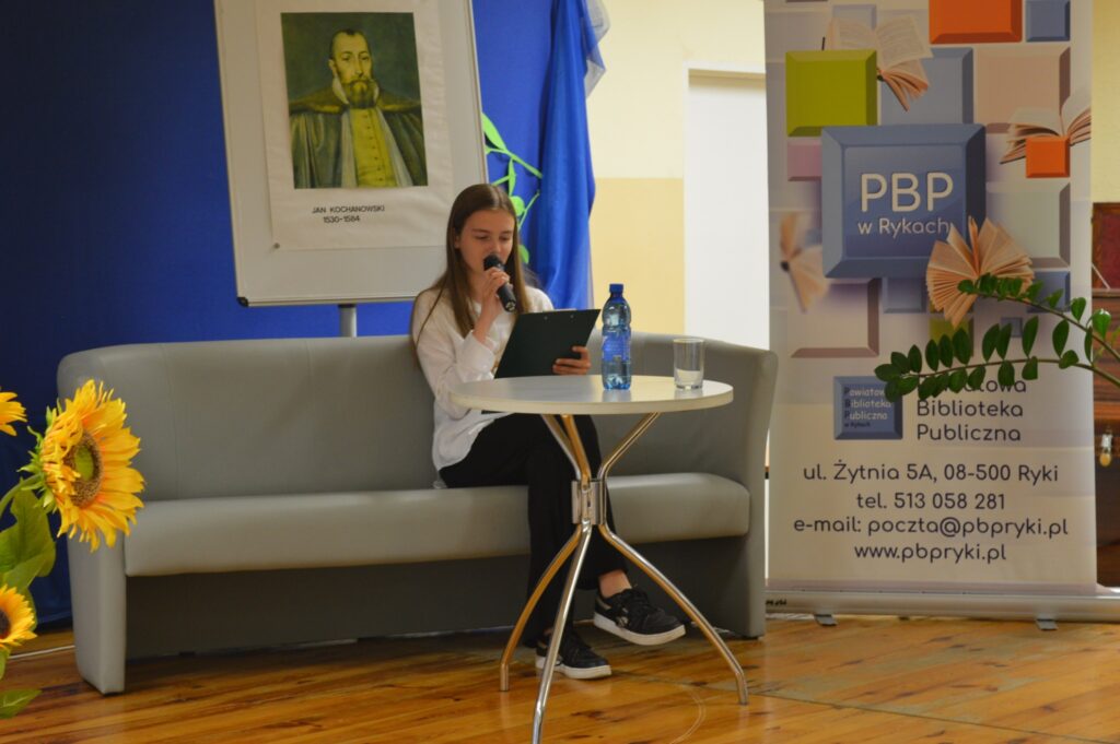 Czyta dziewczyna, siedzi, z boku żółte słoneczniki, tło narodowe czytanie, scena